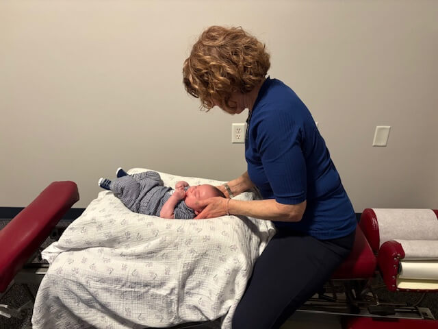 Pediatric chiropractor supporting a baby